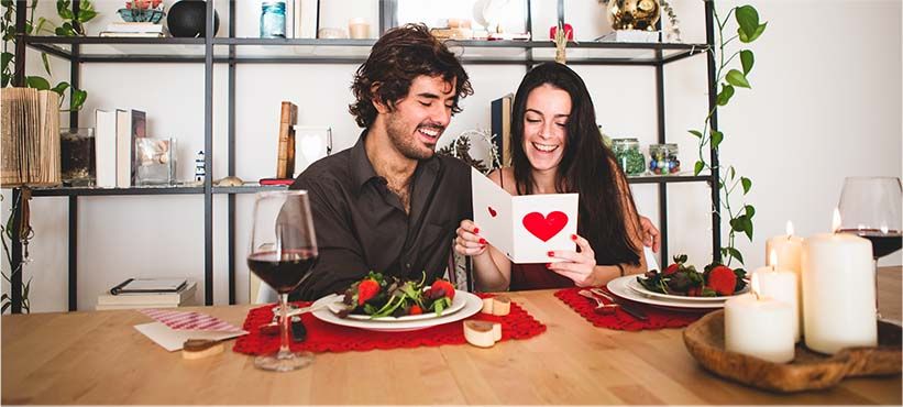 Couple reading valentines card at romantic dinner.